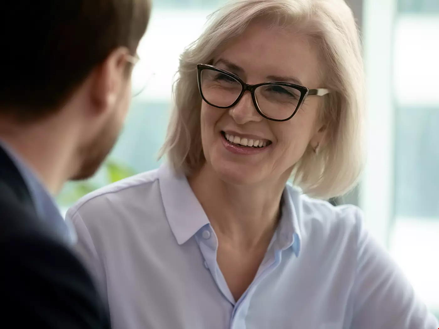 Kvinnlig senior chef i samtal med yngre manlig medarbetare.