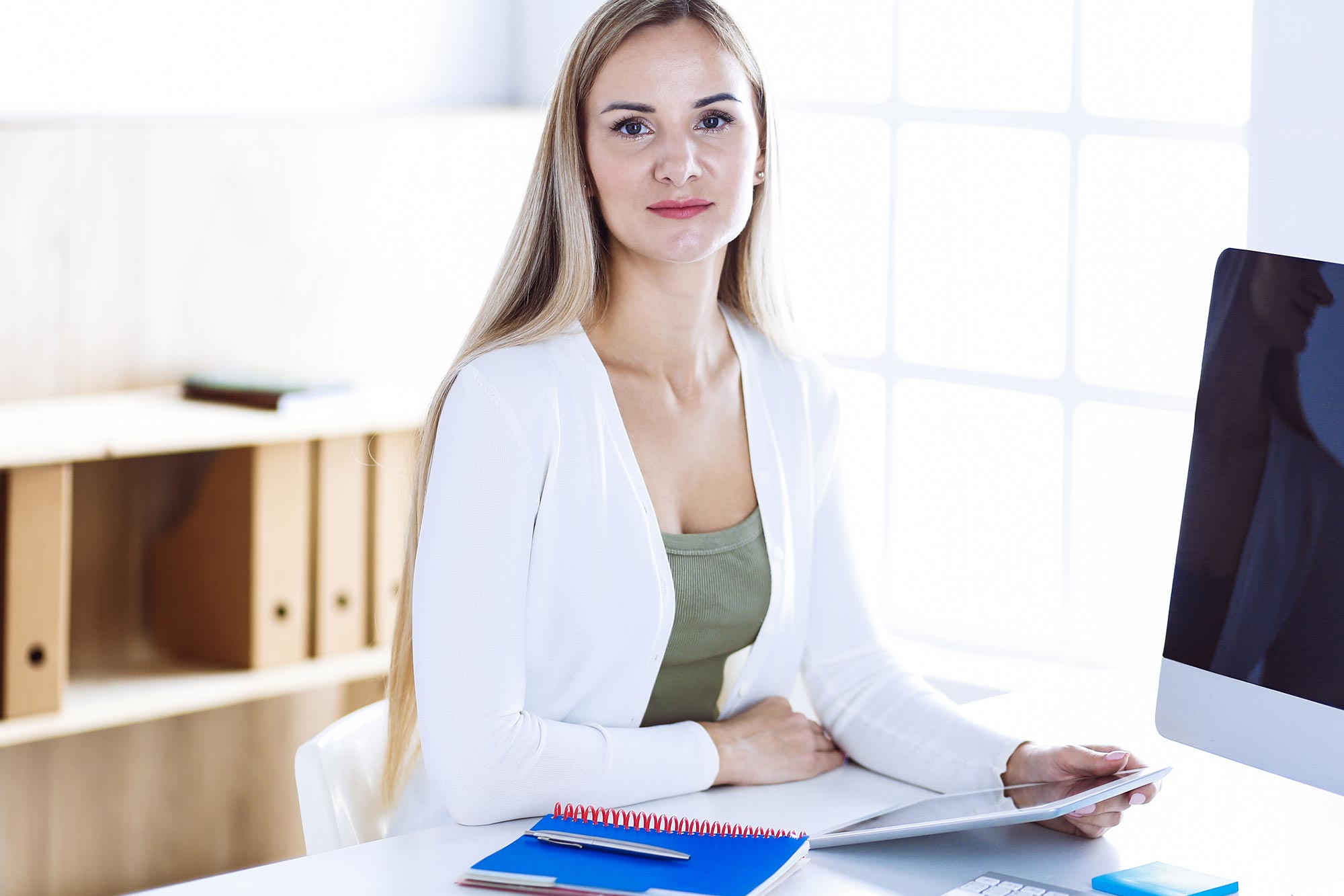 en kvinna  sitter på kontor utbildad ekonom klädd i ljus kofta akavia aspekt