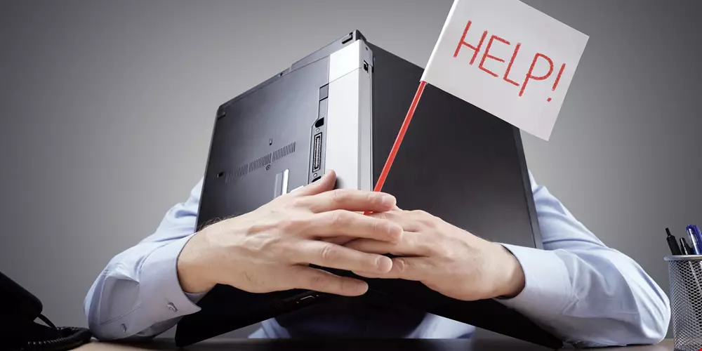 En medarbetare gömmer sig under sin laptop och håller upp en skylt som säger Hjälp Akavia Aspekt