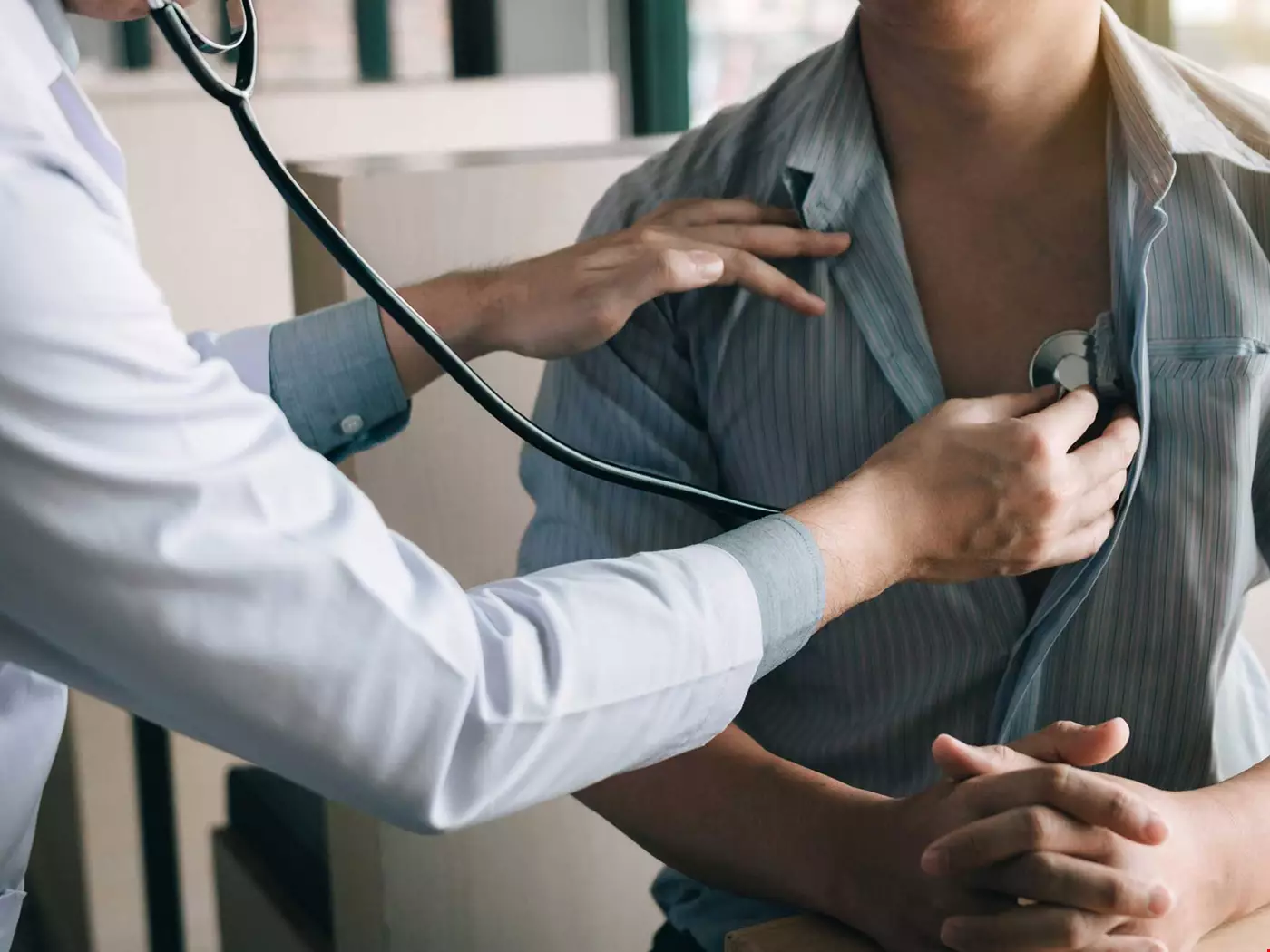 Läkare lyssnar på hjärtat hos patient 