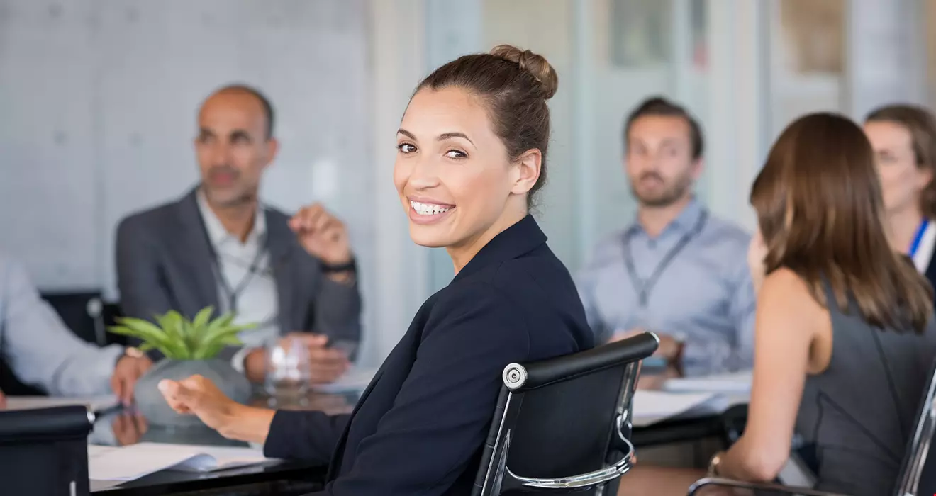 En grupp kollegor runt ett konferensbord, de ser glada ut och verkar ha roligt på jobbet. En kvinna ser ut att vara chef.